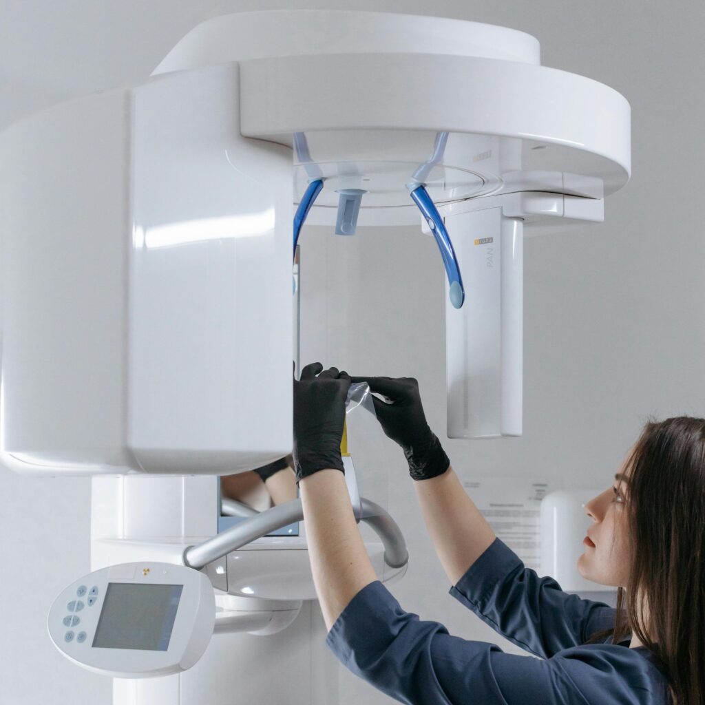 Female dental technician adjusting advanced x-ray machine at clinic.